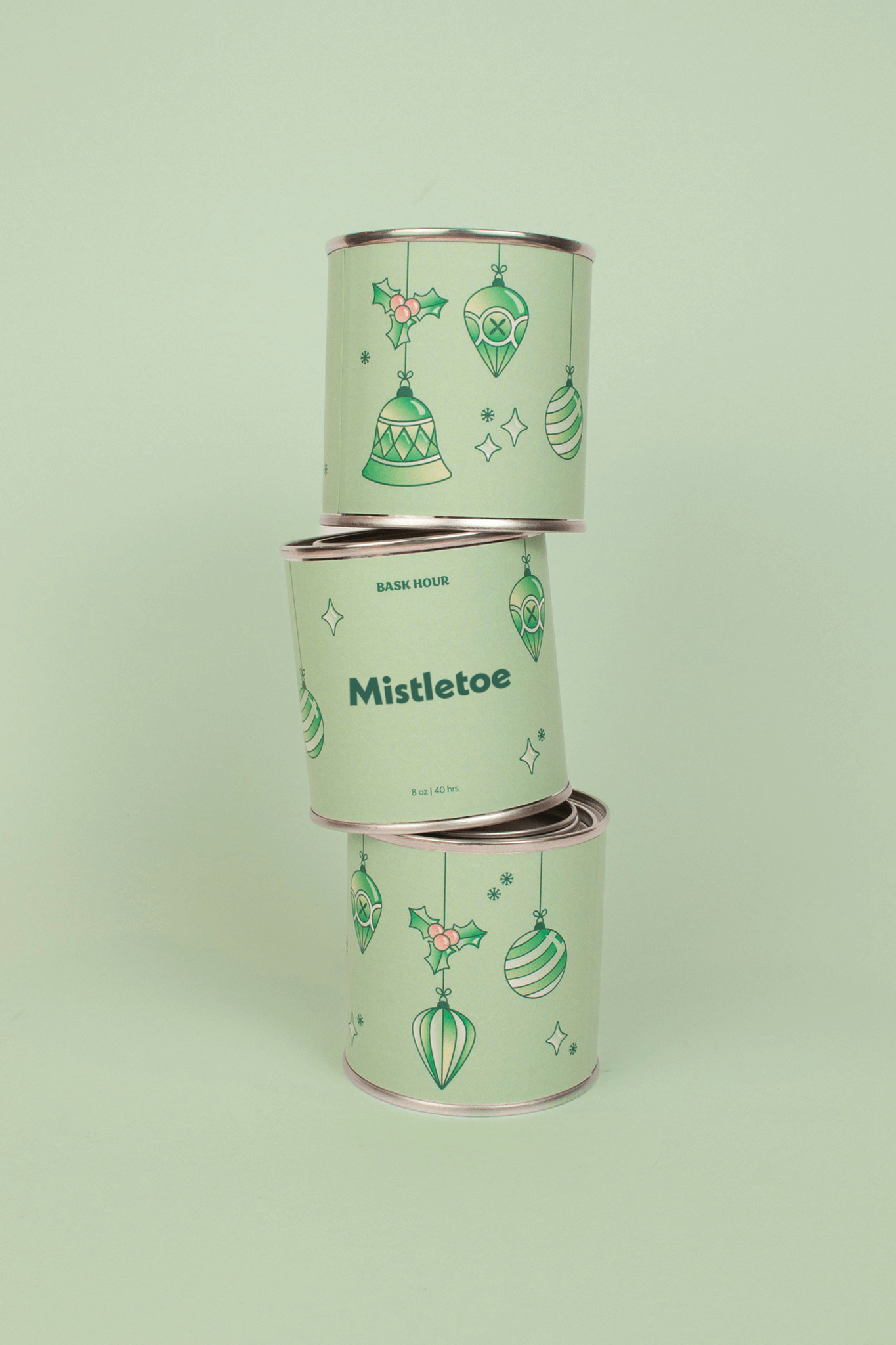Three stacked cylindrical containers with 'Mistletoe' text and decorative designs on a light green background