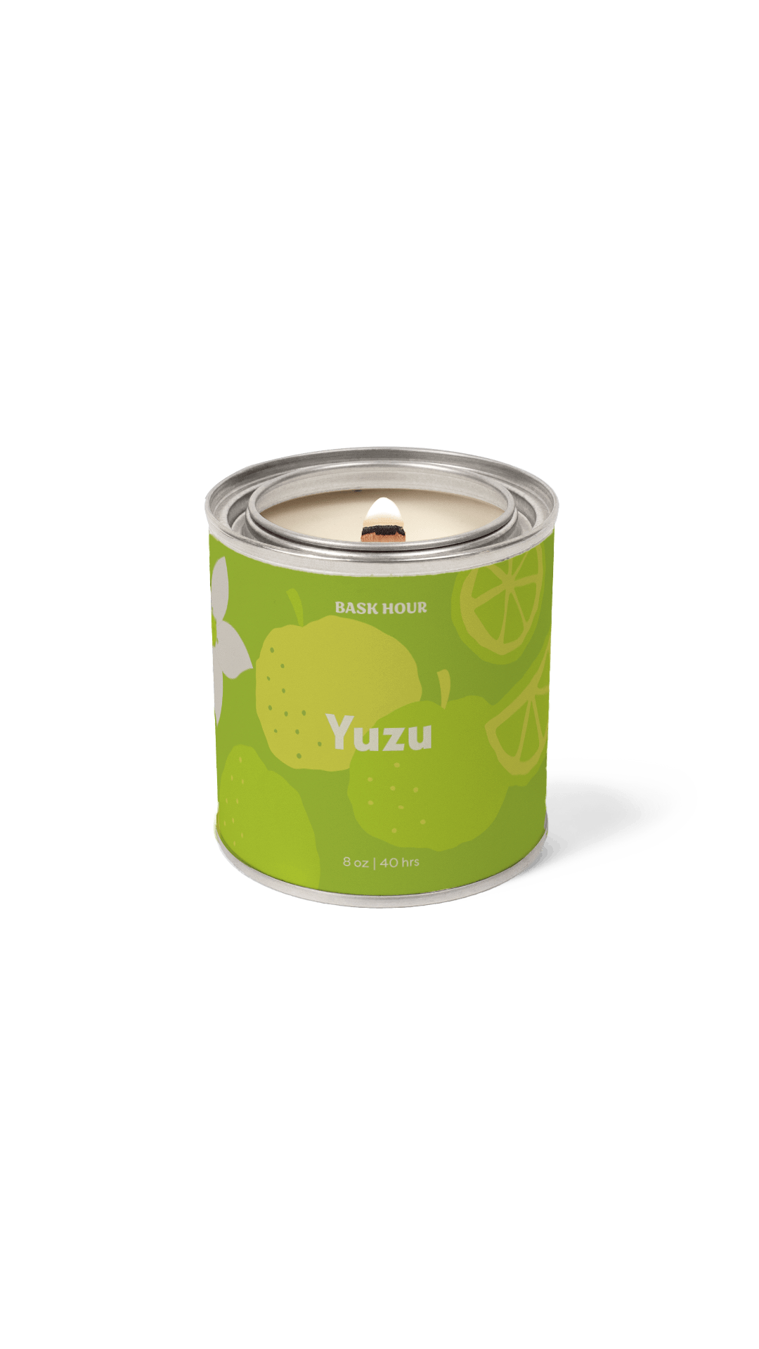 A single cylindrical scented candle in a metallic tin with a bright green label reading 'Yuzu' and 'Bask Hour.' The label includes yellow citrus illustrations and a white flower graphic.