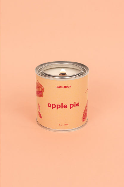 A natural, toxin-free apple pie scented candle in a simple glass jar. The candle features a smooth wax surface with a warm, golden hue. A single cotton wick is centered, and the label highlights its all-natural ingredients and comforting apple pie aroma.