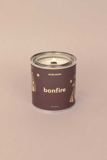 A natural, toxin-free bonfire scented candle in a rustic glass jar. The candle’s wax has a rich, smoky amber color, with a single cotton wick in the center. The label emphasizes its all-natural ingredients, evoking the warm and earthy scent of a bonfire.