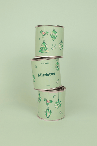 Three stacked cylindrical containers with 'Mistletoe' text and decorative designs on a light green background