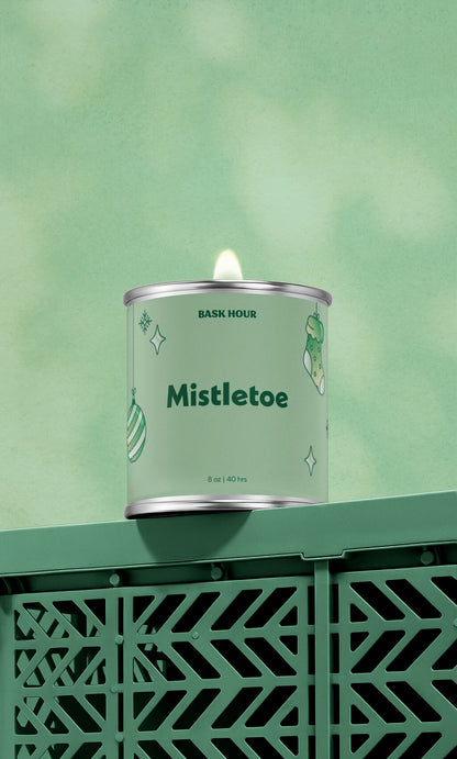 Candle in a green container labeled 'Mistletoe' on a green background
